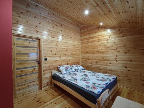 1 dormitorio con 1 cama en una habitación de madera en Chata pod lasem, en Zatory