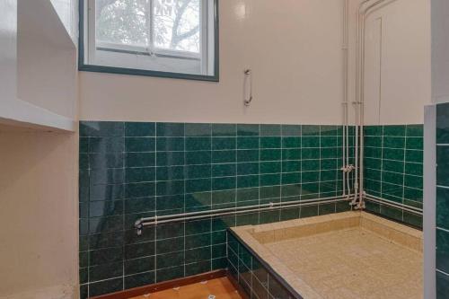 baño de azulejos verdes con ducha y ventana en Beautiful farmhouse near Amsterdam center, en Watergang