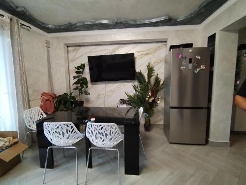 ein Wohnzimmer mit einem Kühlschrank, einem Tisch und Stühlen in der Unterkunft Chambre 3 lits simples cuisine commune in Saint-Pierre-du-Mont