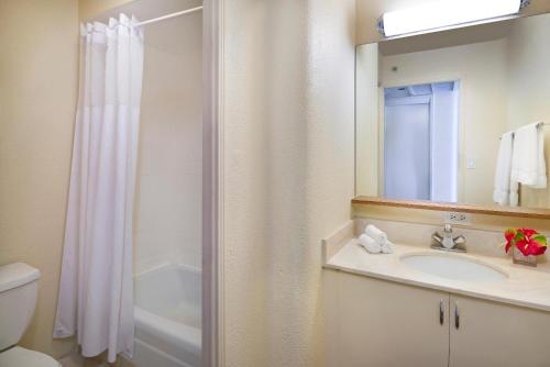 a bathroom with a sink and a shower with a mirror at Beautiful Suites at Ohia Waikiki Honolulu in Honolulu