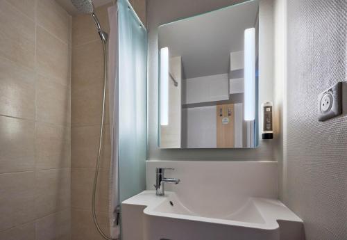 uma casa de banho com um lavatório, um espelho e um chuveiro em B&B HOTEL Honfleur em Honfleur