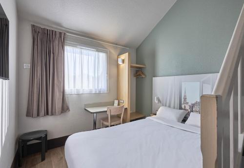 una camera d'albergo con letto e scrivania di B&B HOTEL Honfleur a Honfleur