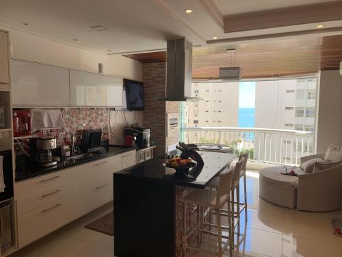 a kitchen with white cabinets and a island with a counter top at Flat botique Guarujá in Guarujá