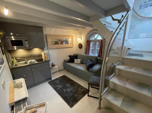 ein kleines Wohnzimmer mit einem Sofa und einer Küche in der Unterkunft Huus Lüttenblick Single Wohnung Kajüte in Südstrand