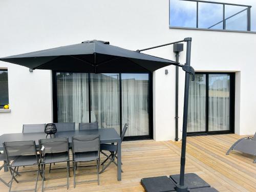 a table with chairs and an umbrella on a patio at Villa Bréhat vue mer et jacuzzi in Tréveneuc