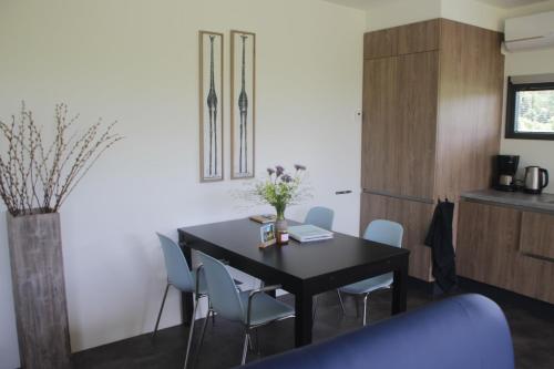 a dining room with a black table and chairs at Sfeervol chalet midden in de natuur in Halle