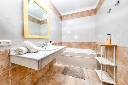 ein Badezimmer mit einem Waschbecken, einer Badewanne und einem Spiegel in der Unterkunft Casa Iria in Playa Blanca