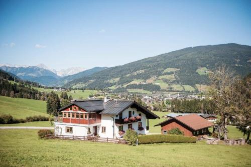 a house in a field with mountains in the background at Haus Kirchgasser in Altenmarkt im Pongau