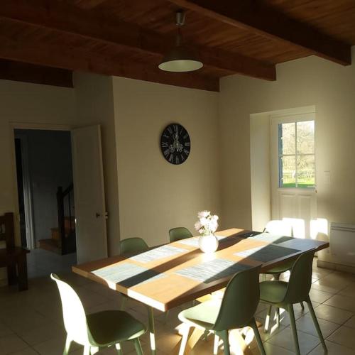 une table à manger avec des chaises et une horloge murale dans l'établissement Résidence KREIZ AN AVEL, à Plobannalec-Lesconil