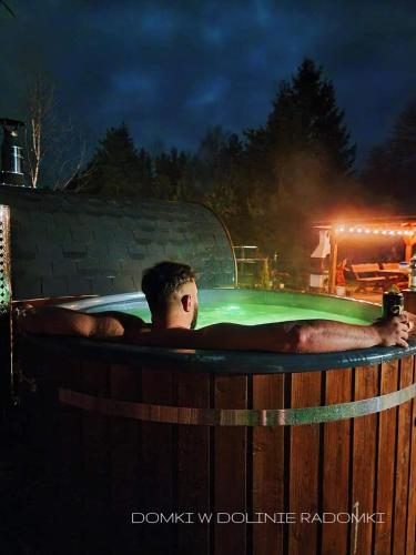 un hombre tendido en un jacuzzi por la noche en Domki w Dolinie Radomki, 