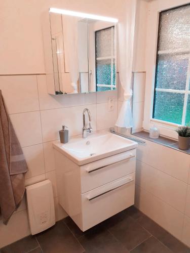 a white bathroom with a sink and a mirror at Fewo Rosalie in Norddeich