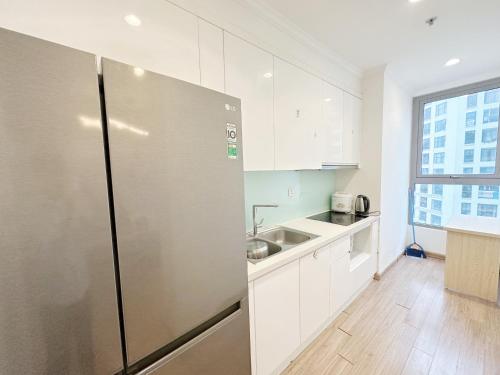 La cuisine est équipée de placards blancs et d'un réfrigérateur en acier inoxydable. dans l'établissement City Center 4BR Apartment, à Hanoï