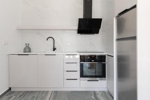 a white kitchen with a sink and a refrigerator at Marble Luxury Suites in Karteros