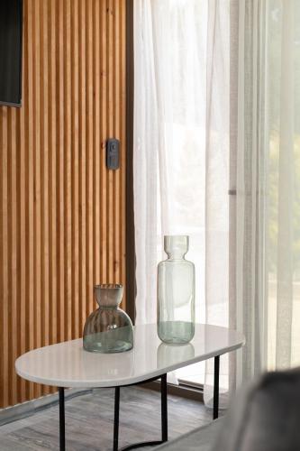 a table with two glass vases on it next to a window at Marble Luxury Suites in Karteros