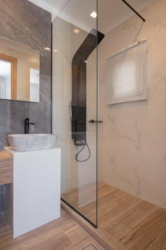 a bathroom with a sink and a glass shower at Marble Luxury Suites in Karteros