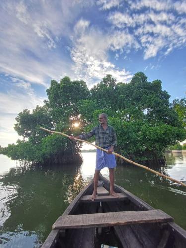 a man standing in a boat with a stick at Mundro Garden Homestay in Munroe Island