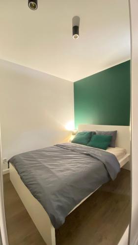 a bedroom with a bed with a green wall at Apartament Złocień in Krakow