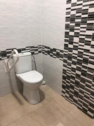 a bathroom with a toilet with a black and white tiled wall at Hotel Kasa in Las Palmas de Gran Canaria