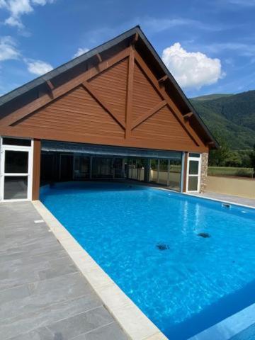 une grande piscine bleue avec un bâtiment dans l'établissement Le nid douillet du Pic d'Aran, à Luchon
