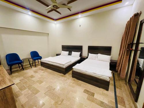 two beds in a room with two chairs and a ceiling at Hotel Bed & Rest Airport in Karachi