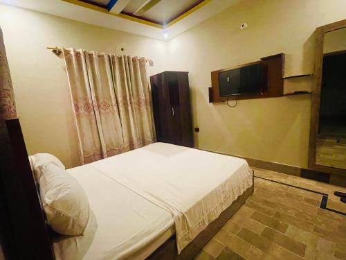 Hotel Bed & Rest Airport في كراتشي: غرفة نوم بسرير وتلفزيون بشاشة مسطحة