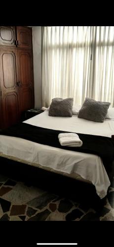 um quarto com uma cama com duas almofadas e uma janela em Host Apt• central em Pereira