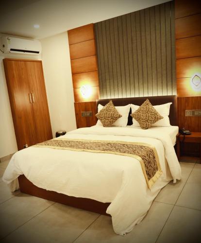a bedroom with a large bed with white sheets and pillows at Silverstone Inn in Nedumbassery