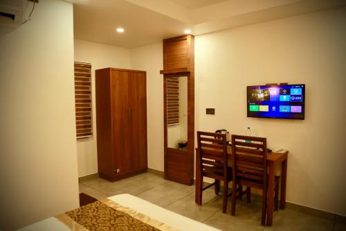 a dining room with a table and a television on the wall at Silverstone Inn in Nedumbassery