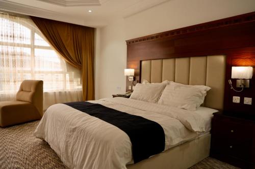 a bedroom with a large bed and a chair at Al-faleh Hotel in Al Baha