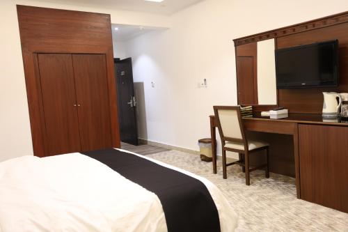a hotel room with a bed and a desk and a television at فندق الفالح للوحدات الفندقيه in Al Baha