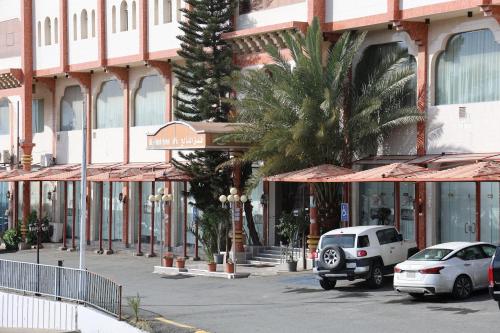 a street with cars parked in front of a building at فندق الفالح للوحدات الفندقيه in Al Baha
