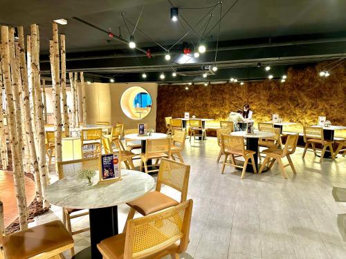 Un restaurant avec des tables et des chaises, et une personne en arrière-plan. dans l'établissement Scarletz Suites KLCC by M Suites, à Kuala Lumpur