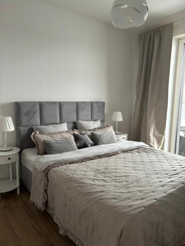 a white bedroom with a large bed and two lamps at Baltic Marina Residence z mini SPA in Kołobrzeg