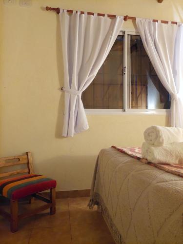 1 dormitorio con 1 cama y ventana con silla en Aroma de campo en Chascomús