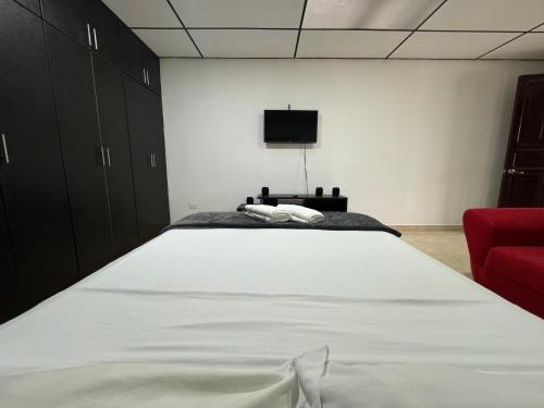 um quarto com uma grande cama branca e uma cadeira vermelha em Acogedor apartaestudio ubicado en la zona rosa de Pereira em Pereira