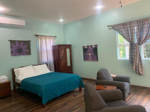 a bedroom with a bed and a couch and a chair at Lily Pad II in Caye Caulker
