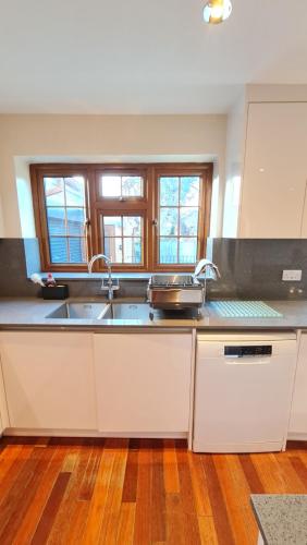 a kitchen with a sink and two windows at Luxury London House Sleeps x 16, Free Parking, Free Wifi, Garden Patio, Close to tube line easy access to Central London in Ilford