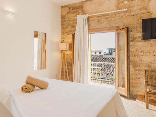 ein Schlafzimmer mit einem Bett und einem großen Fenster in der Unterkunft Hotel Boutique Can Pocovi in Sant Llorenç des Cardassar