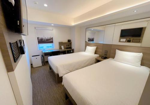 um quarto de hotel com duas camas e uma televisão em Smile Hotel Sapporo Susukino Minami em Sapporo