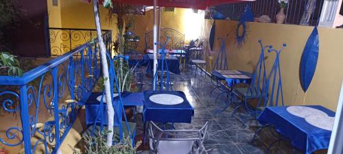 a restaurant with blue tables and chairs and an umbrella at Riad Le Lieu in Tiznit