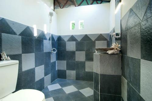 a bathroom with a black and white tiled shower at Thank You Bungalow in Gili Meno