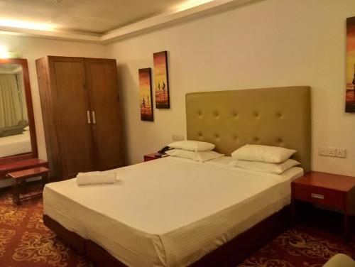 een slaapkamer met een groot bed met 2 kussens bij Ramadia Ran Mal Holiday Resort in Moratuwa