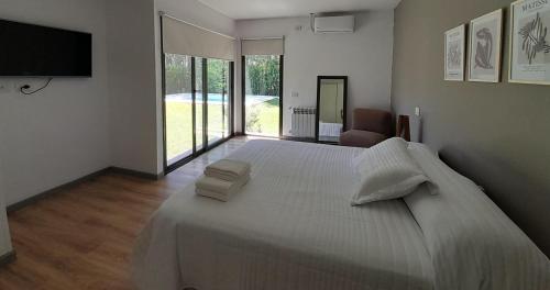1 dormitorio con 1 cama blanca grande y TV en Los Álamos Vistalba en Luján de Cuyo