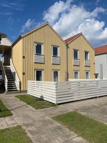 a yellow building with a white fence in front of it at Udsigten in Rudkøbing