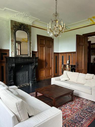 a living room with white furniture and a chandelier at Château de Porcheresse in Daverdisse