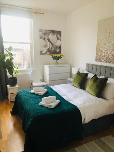 a bedroom with a large bed with green pillows at 20 min to central London- 2 bedrooms apartment in London