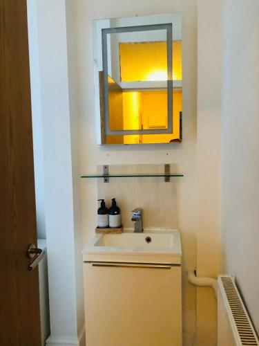 a bathroom with a sink and a mirror at 20 min to central London- 2 bedrooms apartment in London