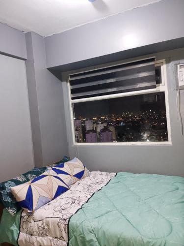 a bedroom with a bed and a window with a city at K2K place in Manila