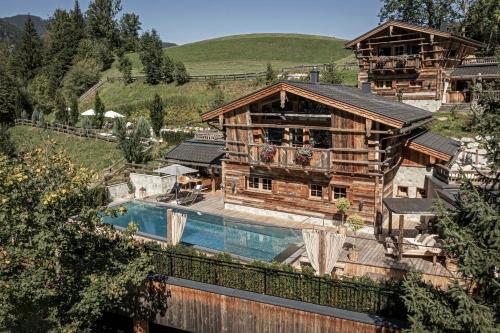 a log house with a swimming pool in front of it at Pool Luxury Lodge in Wagrain