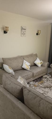 um sofá castanho com almofadas na sala de estar em Tj homes-Airportview em Nairobi